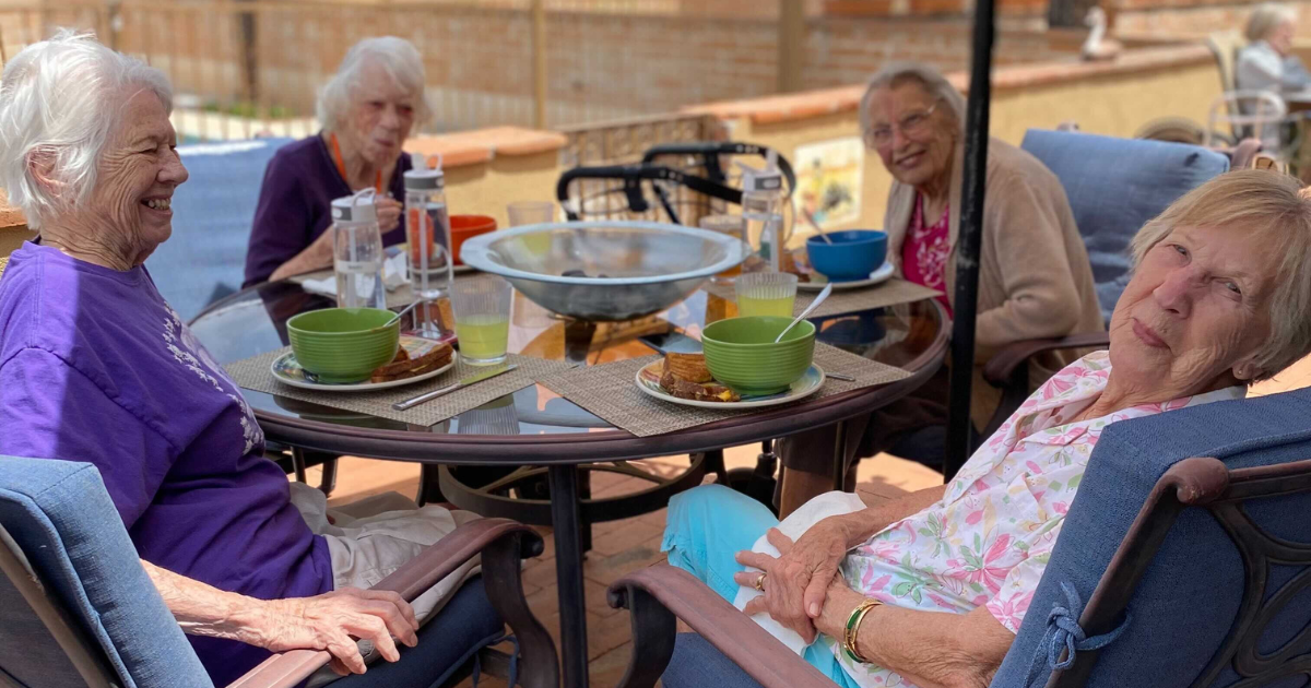 Seniors at an assisted living facility enjoy a meal together.