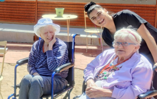 A caregiver cares for 2 residents outside, showing how high quality memory care and other forms of care can be at Tucson Assisted Living Retreat.