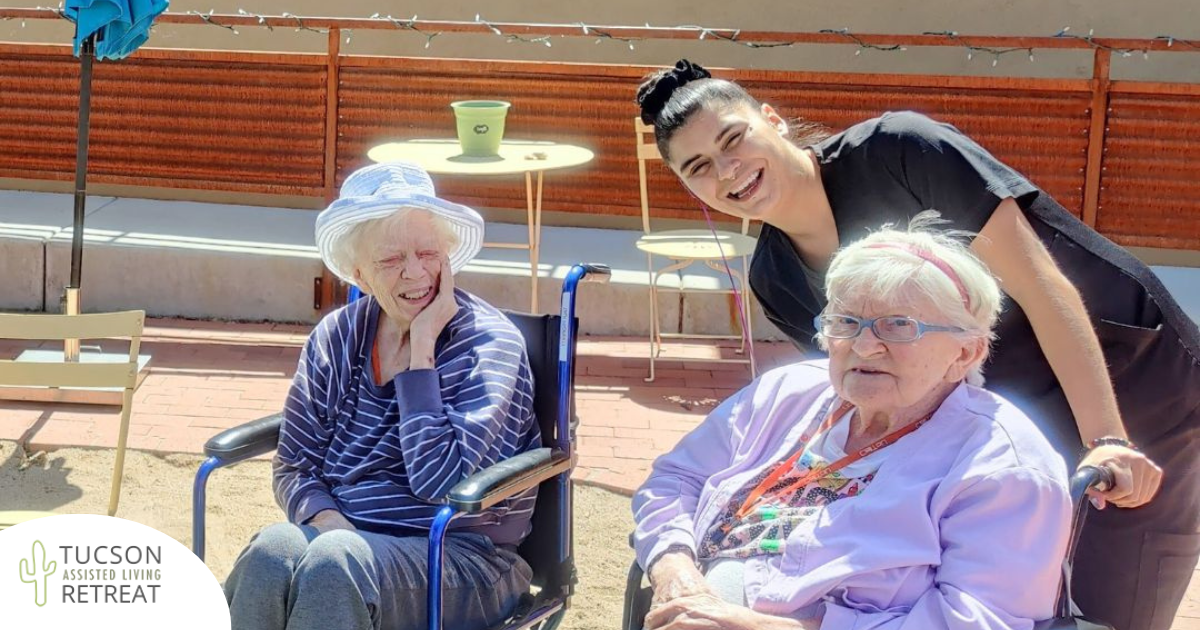 A caregiver smiles as she enjoys caring for two of our residents.
